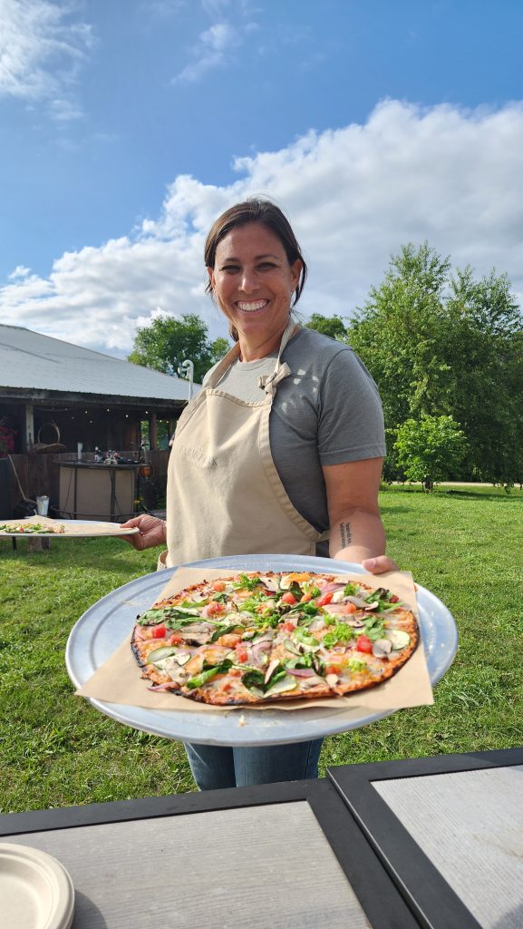 Woman offering pizza at Dancing Yarrow in Eau Claire, Wisconsin.