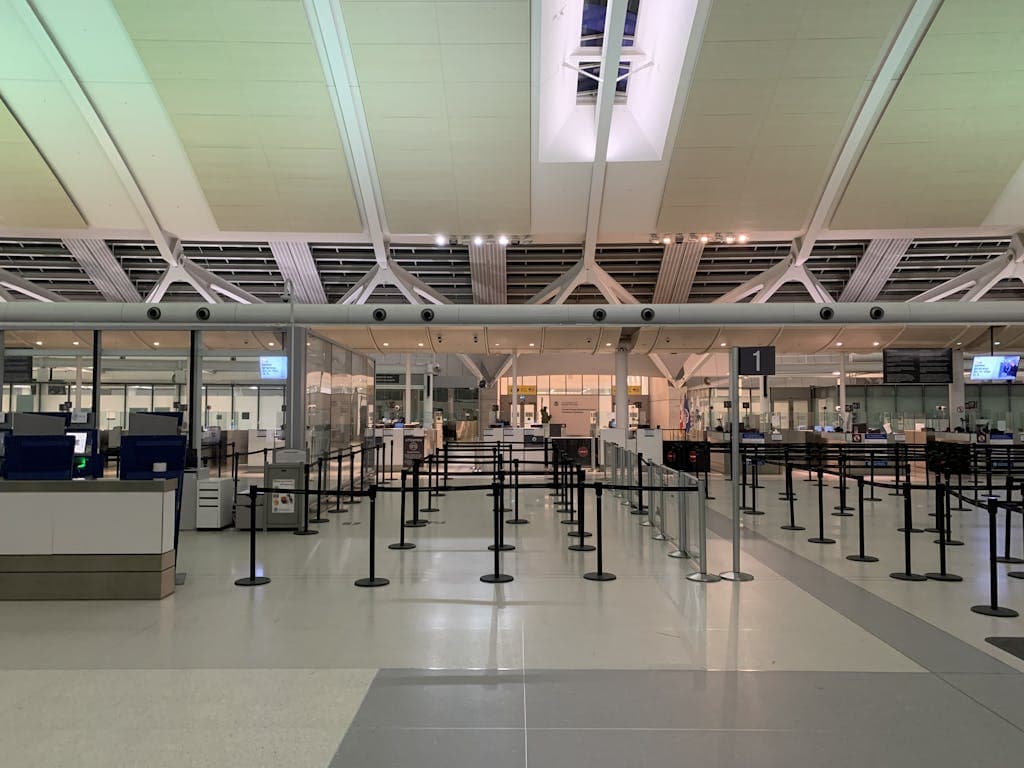 An empty airport security checkpoint with organized rows of stanchions and a modern, well-lit terminal, illustrating accessibility and changes in air travel for passengers with disabilities.