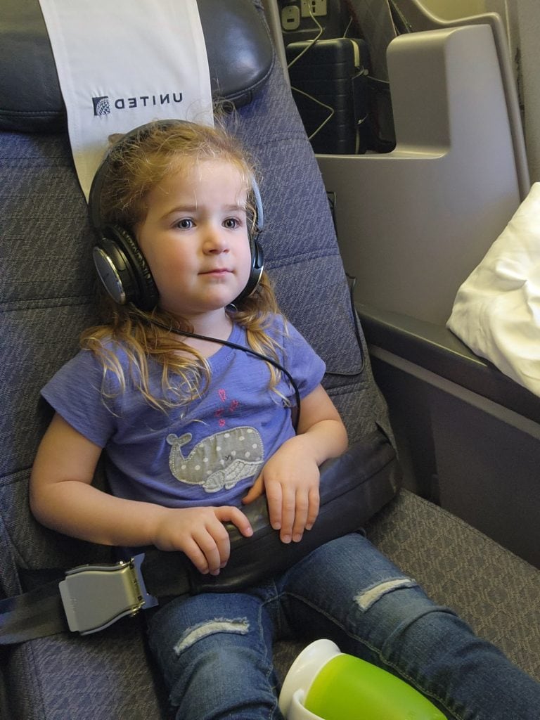 Little girl on a plane with headphones on enjoying her flight.