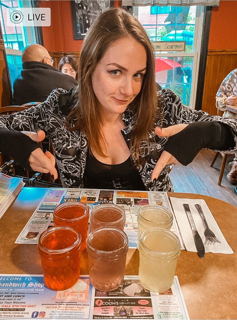 Woman points to a flight of colorful hard ciders served in mason jars at a Red's Sandwich Shop in Salem.